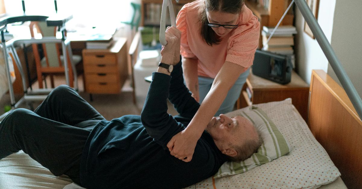 Carer assisting an elderly man to stand up from bed, providing professional home care Bognor Regis to ensure comfort and support for seniors.