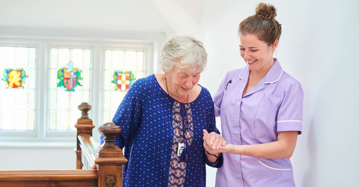 A compassionate carer assisting an elderly woman in a bright living room, representing quality Domiciliary Home Care Services focused on comfort and independence at home.