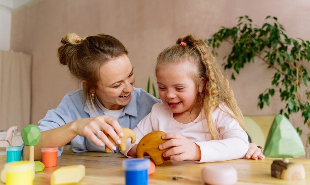 Carer and child playing together on the table, illustrating a warm and supportive overnight child care environment.