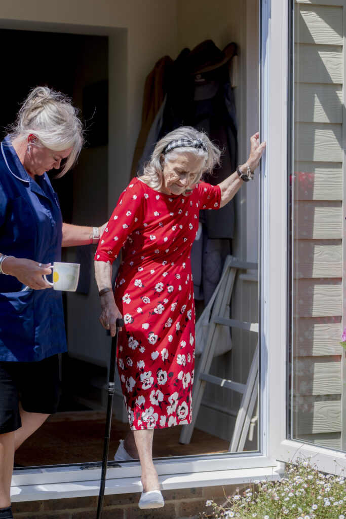 Carer from Choice Care 4U assisting an elderly woman as she walks out the door, representing compassionate mobility and frailty care services.
