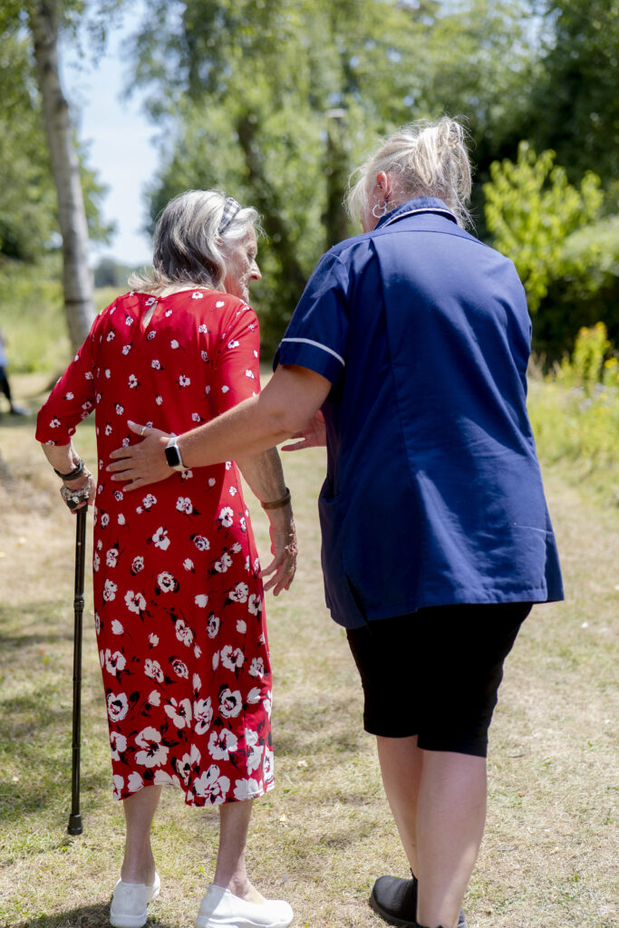 Carer from Choice Care 4U assisting an elderly client with walking outdoors, representing compassionate care at home services in West Sussex.