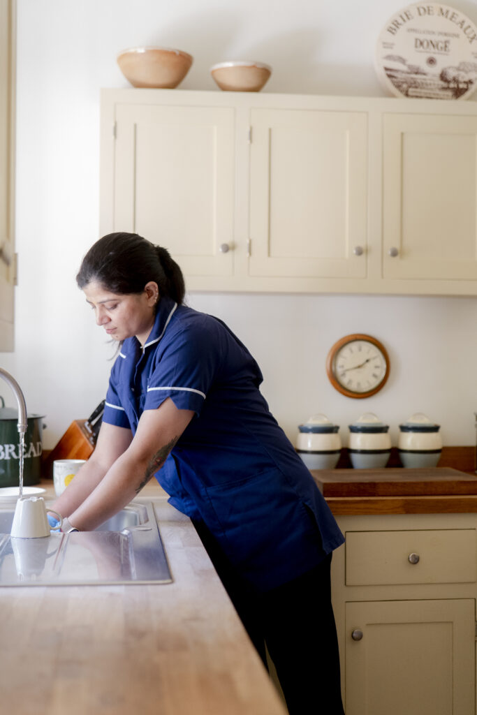 A friendly carer from Choice Care 4U washing dishes in a tidy kitchen, providing compassionate help at home care services.