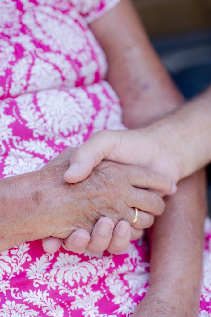 Carer from Choice Care 4U holding the hand of an elderly woman, offering comfort and support as part of compassionate palliative home care services.