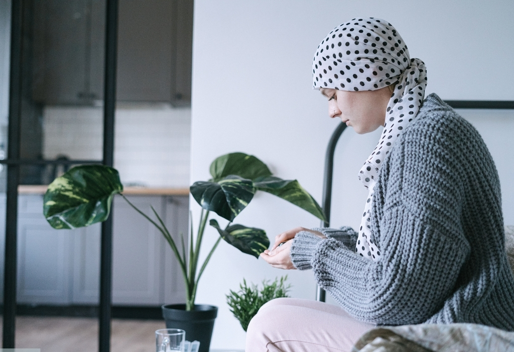 Cancer patient sitting at home holding medicine, reflecting the support of In-Home Cancer Care in Selsey.