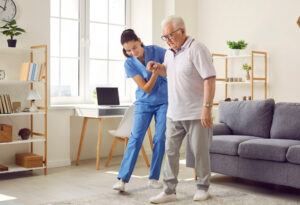 Carer assisting an elderly man with mobility support, providing compassionate care and daily assistance for Motor Neurone Disease at home.