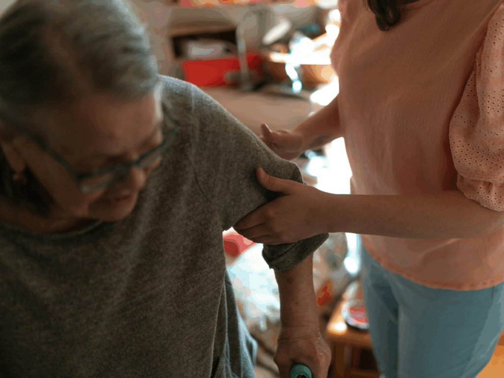 Elderly person receiving support from a carer to stand, illustrating compassionate Parkinson's care in Littlehampton.