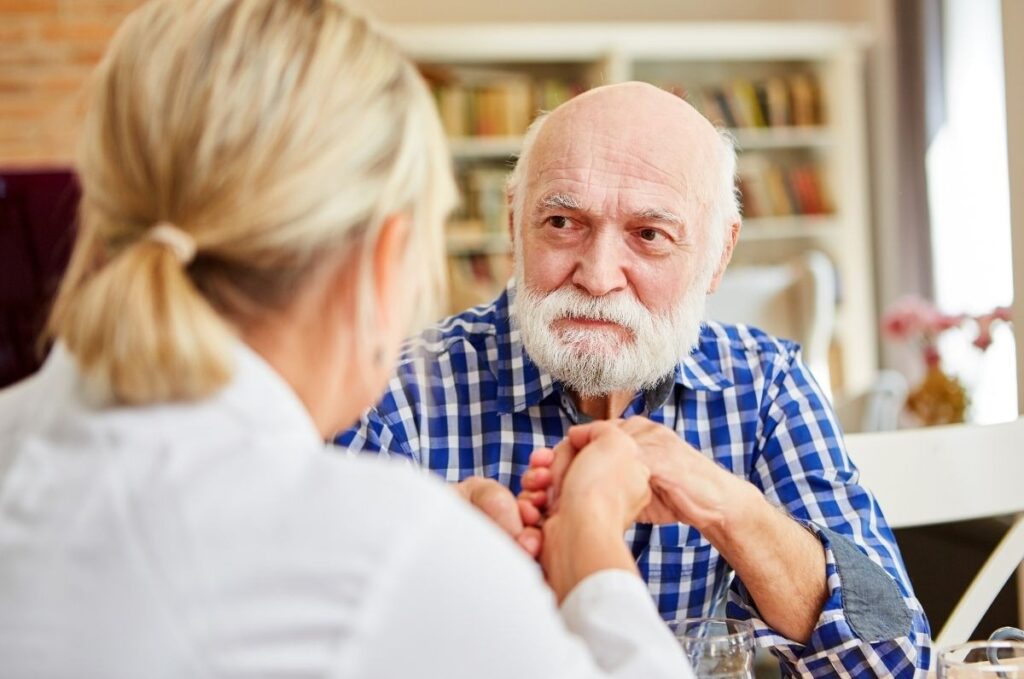 A carer holding a older's man showing dementia home care support